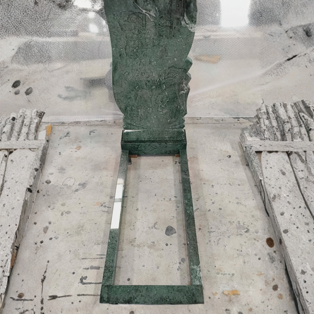 High-polished Imperial Green granite upright headstone featuring a modern wave contour and elegant scalloped side edges, complete with a matching full grave kerb set and base