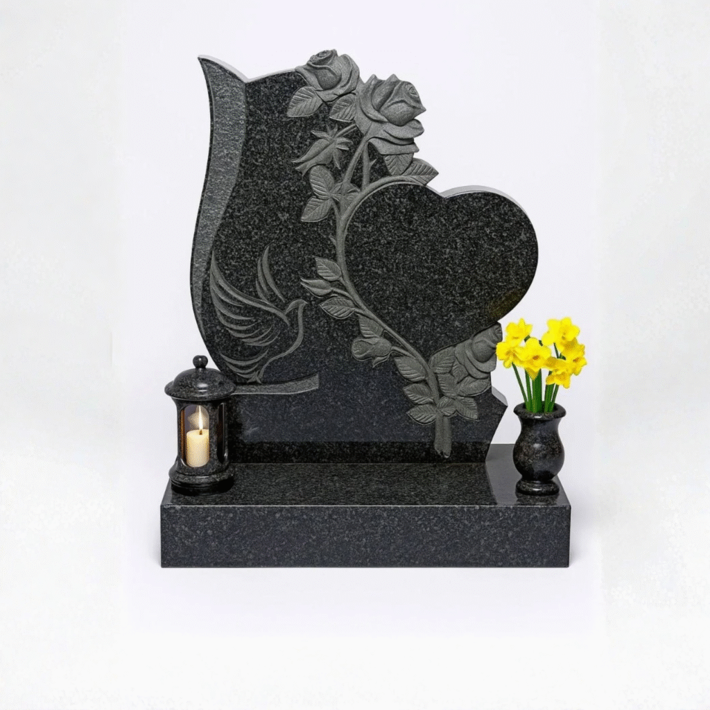 High-polished black granite upright headstone featuring a 3D hand-carved heart, rose vine, and peaceful dove, complete with a matching memorial lantern and flower vase on a solid base.
