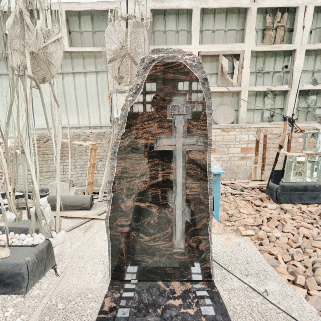 High-polished Indian Aurora multi-color granite headstone with hand-chiseled rock-pitch edges, featuring a large sandblasted Eastern Orthodox Cross in the center.