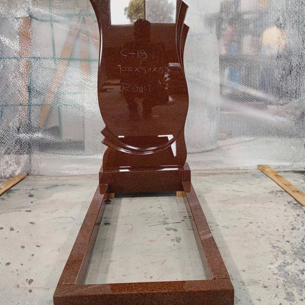 High-polished Imperial Red Indian granite upright headstone featuring a modern curved wave design, complete with a matching rectangular memorial kerb set and base.